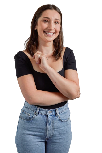 Grace is wearing a black top and blue jeans as she sits on a stool and looks off-camera with a broad smile. 